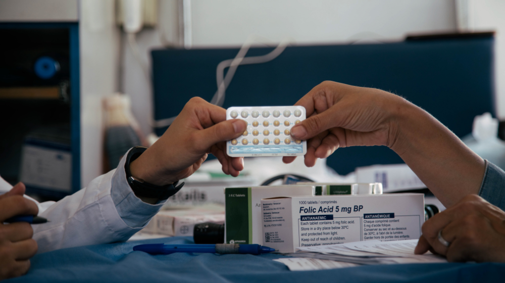 Health workers hold up a one-month pack of oral contraceptives.