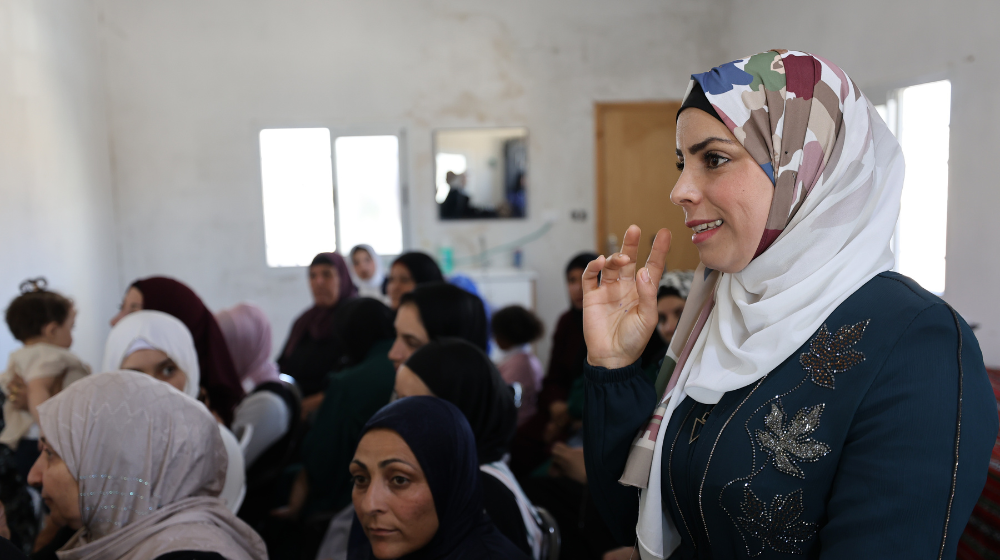 A woman smiles as she addresses a crowd of women