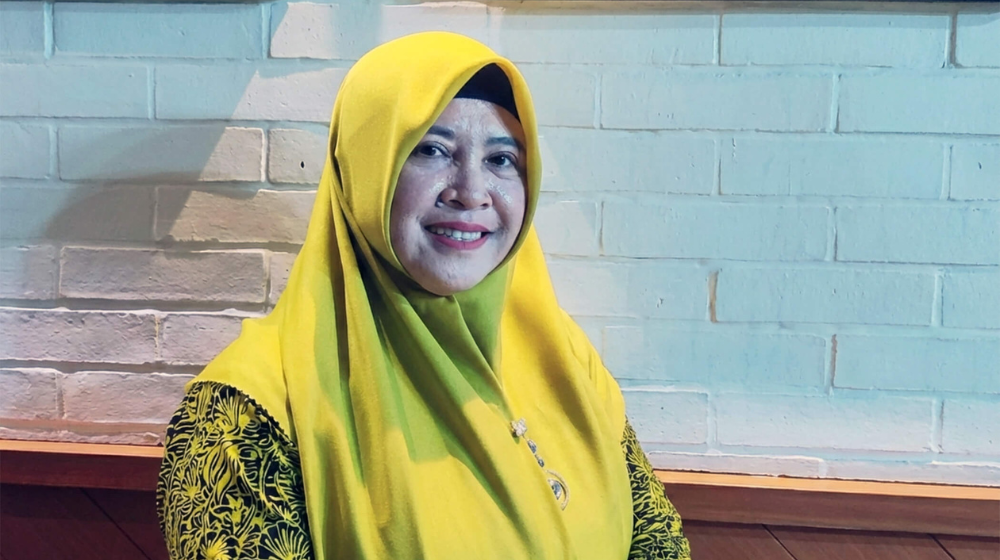  A woman in bright yellow head scarf smiles at the camera