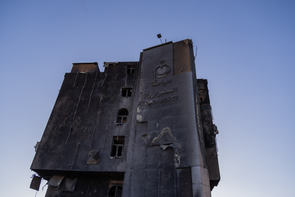 A bombed-out hospital is seen against a blue sky