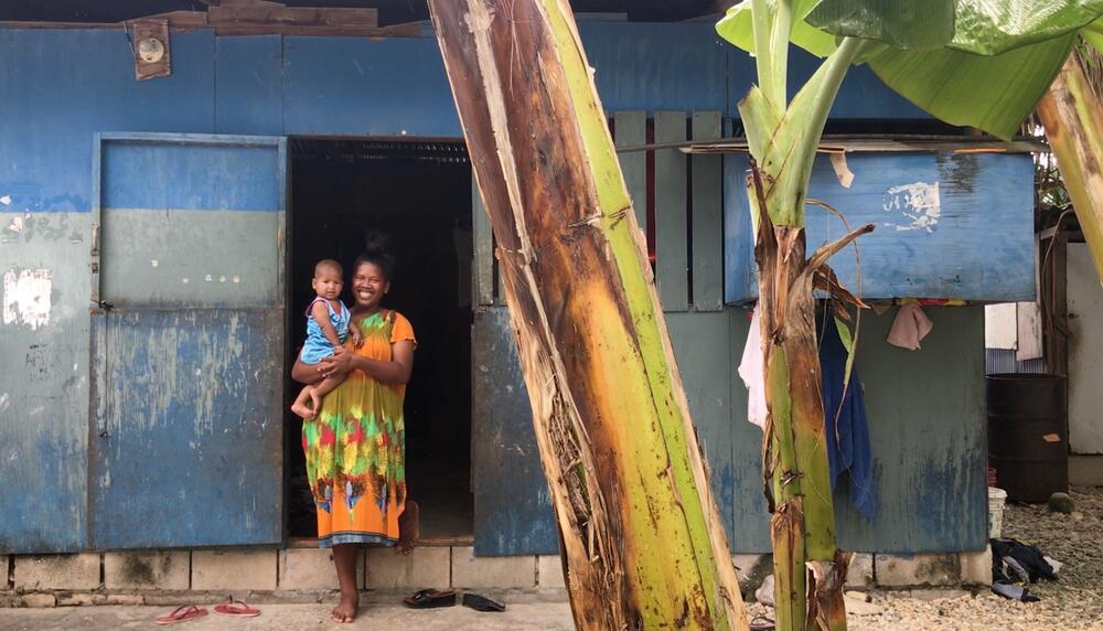 A mother holding her son in her arms in a makeshift house