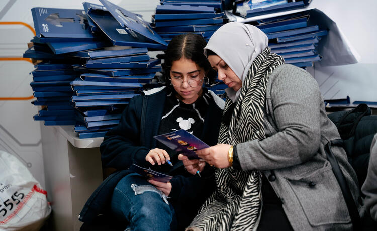  فتاة وامرأة تميل إحداهما على الأخرى أثناء قراءة كتيب معًا.