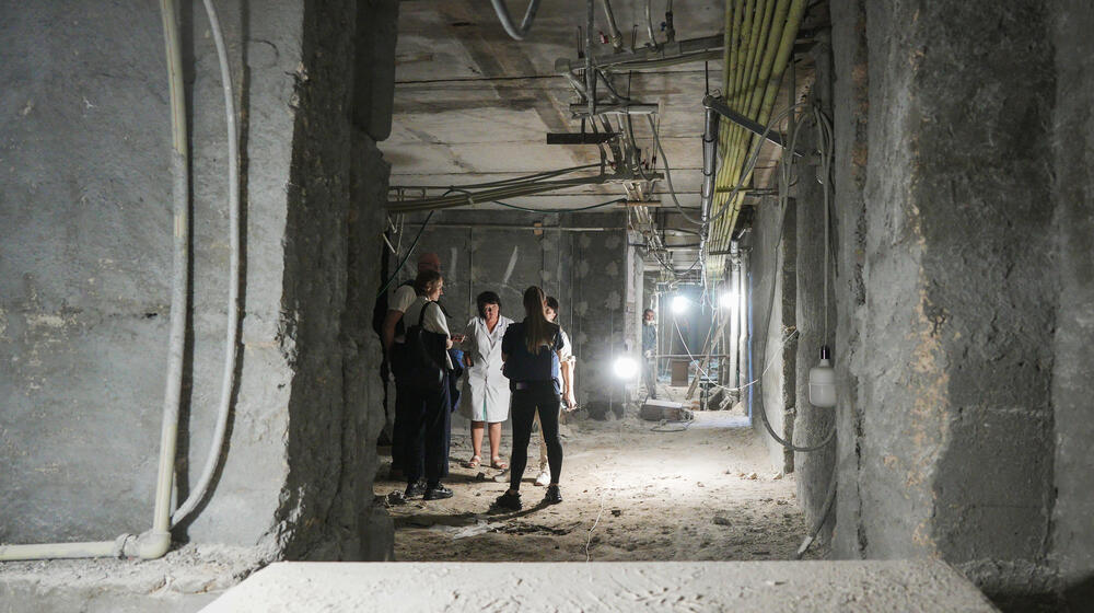 Health workers and builders can be seen through a gap in the thick concrete walls of an underground bunker under construction