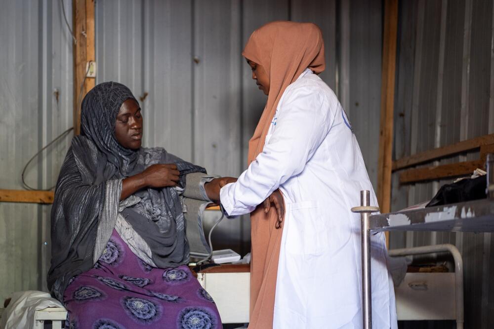 A midwife in a white coat conducts check-up on a pregnant woman. 