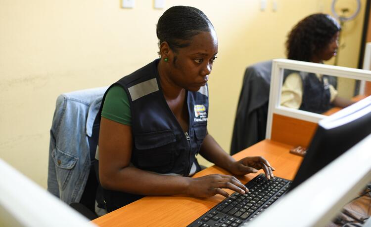  امرأة ترتدي سترة زرقاء تكتب على جهاز كمبيوتر