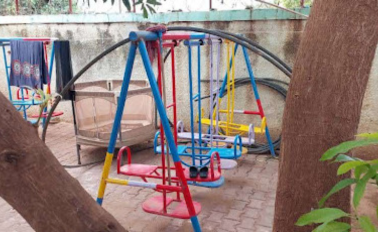 Colourful swings and other playground equipment in a walled-in courtyard.