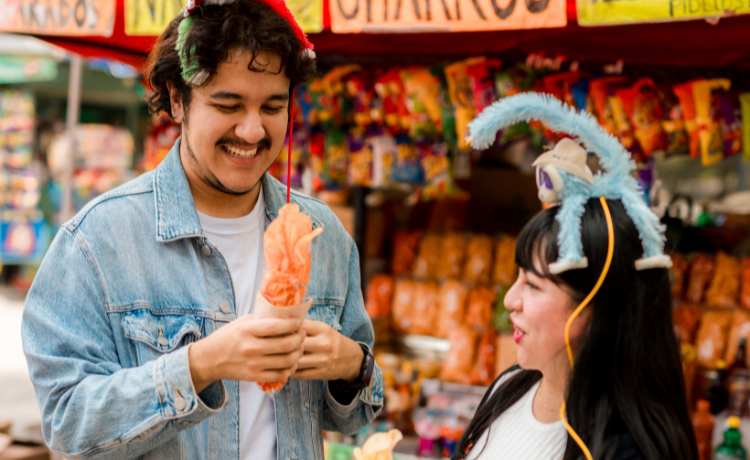 A man and a woman with novelty headwear laugh at a funfair