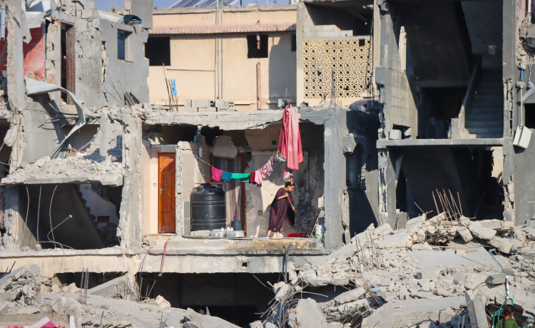 A woman sweeps the floor of an apartment in a bombed-out building