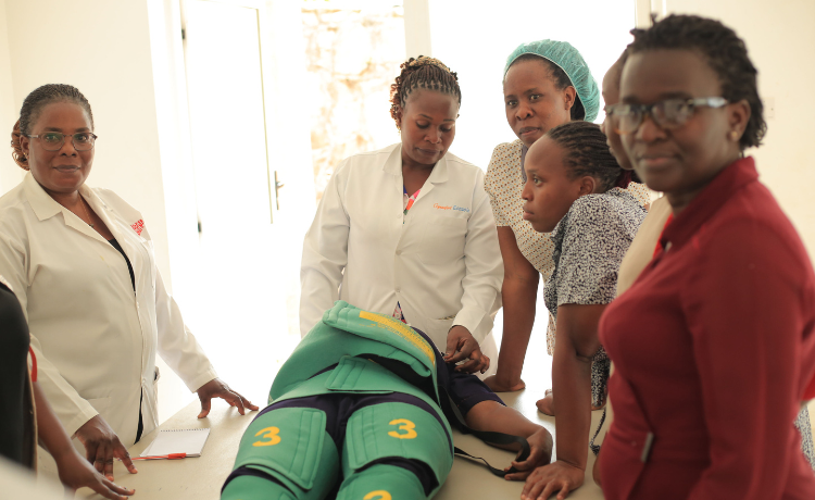 Health workers stand around a person lying on a table; the person on the table wears a ‘non-pneumatic anti-shock garment’, a medical device for controlling blood loss and stabilizing patients in low-resource settings.