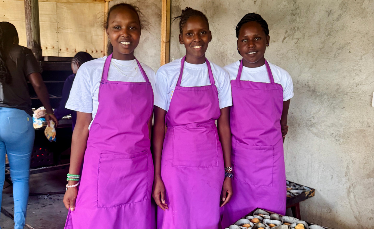 Girls in bright purple aprons point to sweets they have baked in the shelter’s training bakery.
