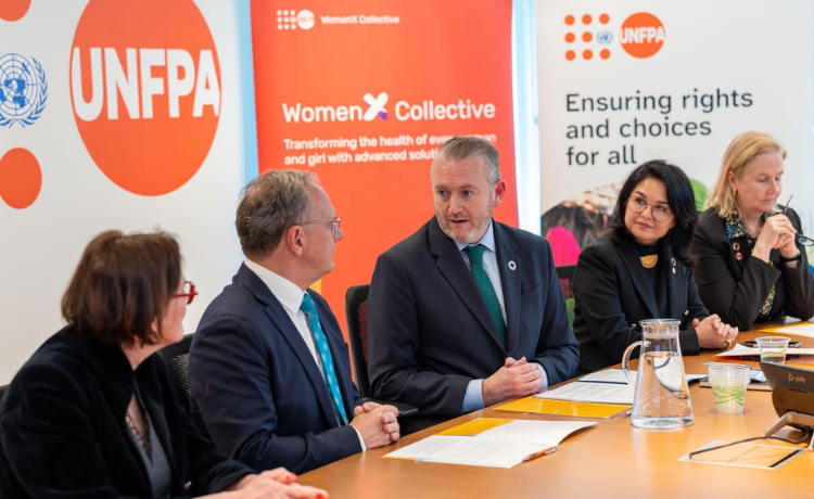 Five officials seated together in discussion at a meeting table during a formal event, engaged in conversation at UNFPA Headquarters.