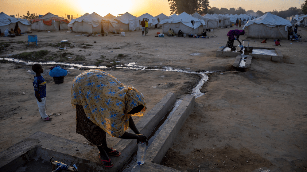 A woman collects clean drinking water in a camp sheltering displaced people after the Chari River flooded in N'Djamena, Chad © UNFPA Chad/Karel Prinsloo
