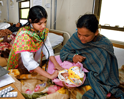 Midwife, mother and child in Pakistan A midwife listens to a baby's heartbeat.