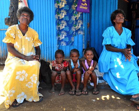 Women and children in Vanuatu Children sit in between two women looking at the sky.