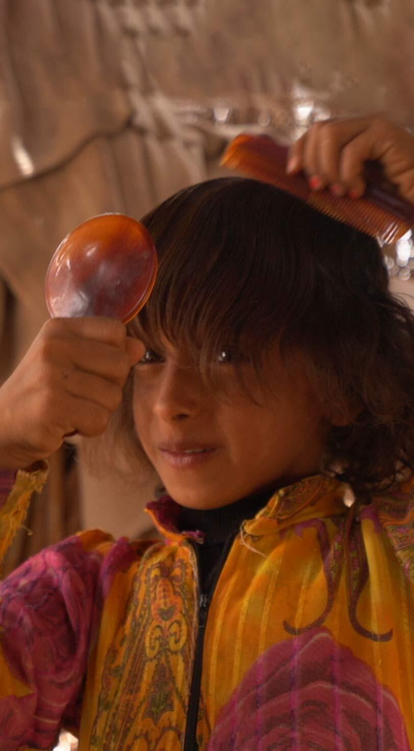 A young girl in a displacement camp in Marib Governorate, Yemen, enjoys a moment of self-care with a dignity kit provided as part of an emergency relief package by UNFPA. The kits include a flashlight, soap, a toothbrush and other personal and menstrual hygiene products to help women and girls maintain their well-being while displaced.