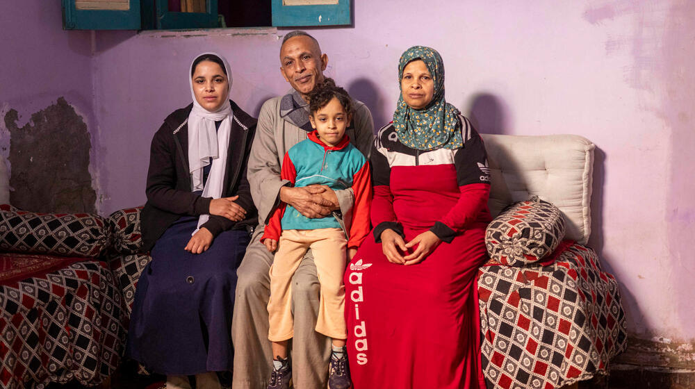 An Egyptian family of four sit together on a sofa. 