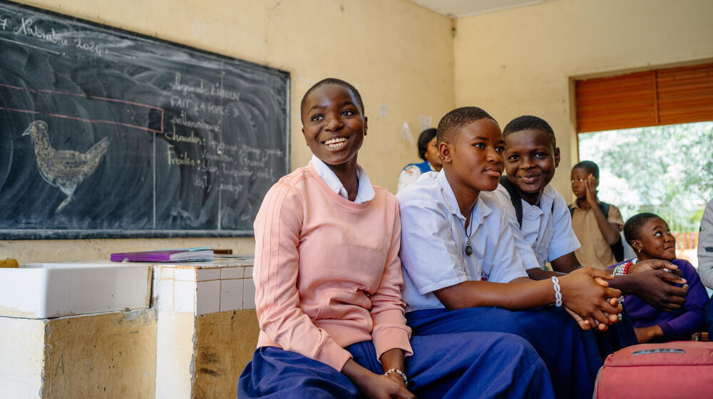 A group of students laugh in a classroom.