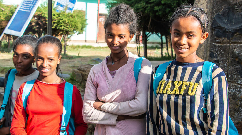 Four young girls look towards the camera with smiles. 