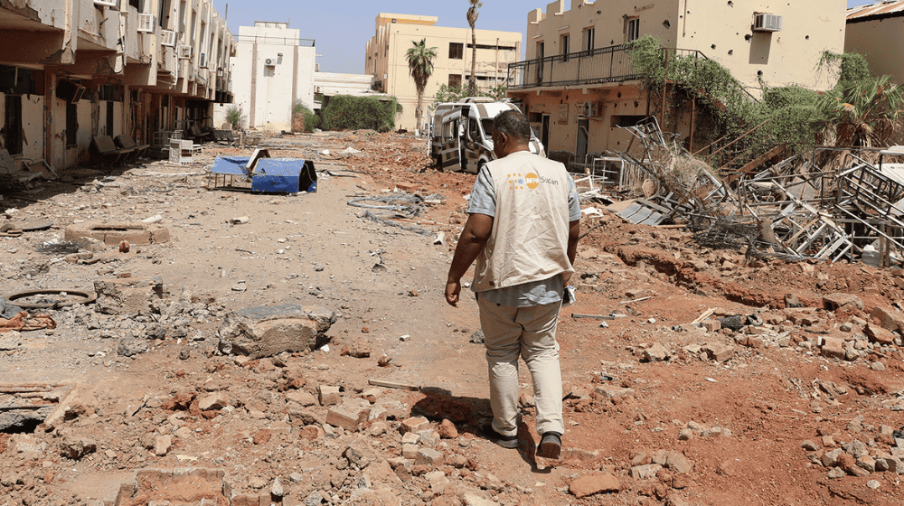 A man walks through a road with destructed hospitals.
