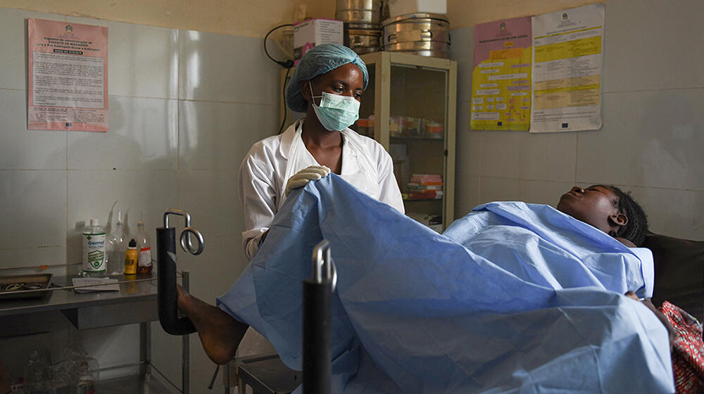 Dans la salle d’accouchement d’un hôpital, une femme accouche sous la supervision d’une agente de santé.