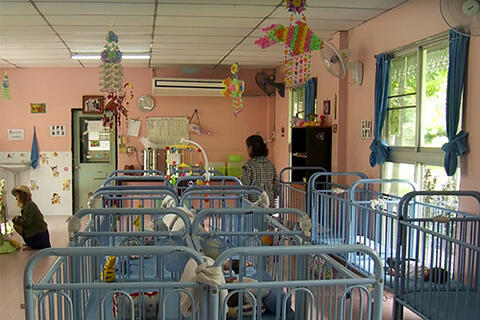 Interior of nursery showing blue bassinets, pink walls, and colorful mobiles