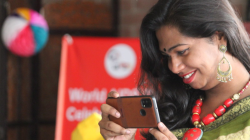 Woman smiles while holding phone.