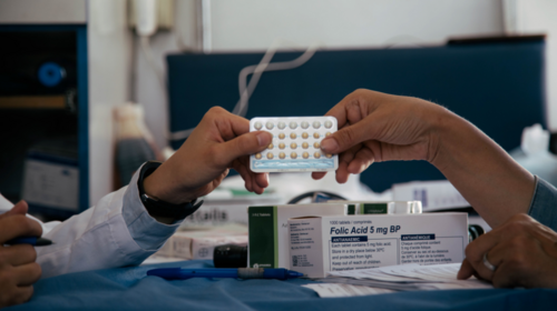 Health workers hold up a one-month pack of oral contraceptives.