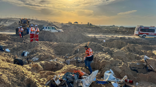 Medical workers, a UN vehicle and an ambulance are seen amid dug up dirt and debris against a setting sun