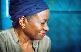 A close up of Dr. Natalia Kanem smiling as she visits with a new mother. 