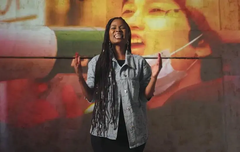 A woman hold up her hands and closes her eyes in deep expression.