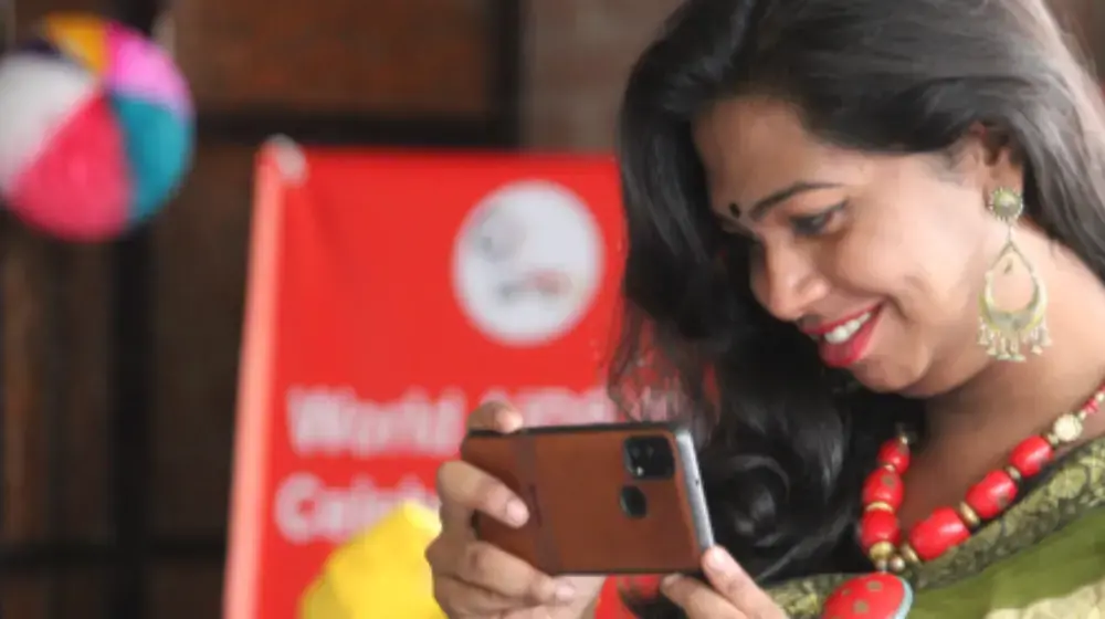Woman smiles while holding phone.