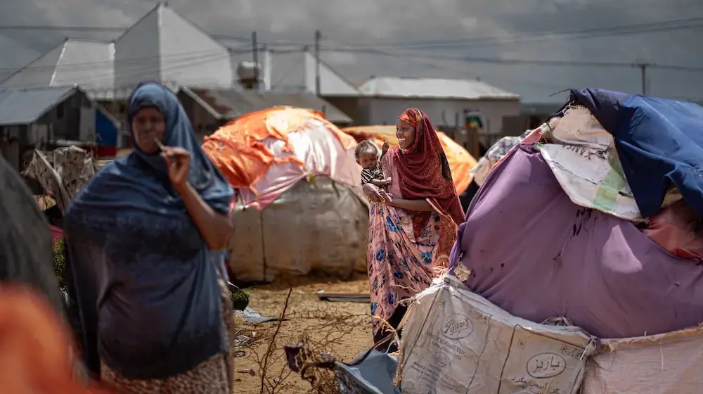 A young girl smiles while carrying her baby on her hip in an IDP camp.