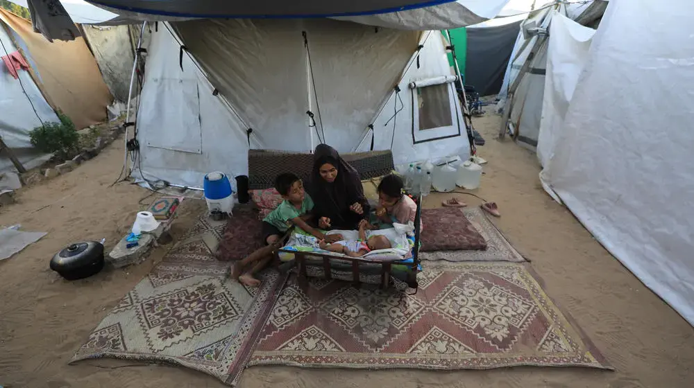 A woman sits outside consulting with a female member of a UNFPA mobile health team.