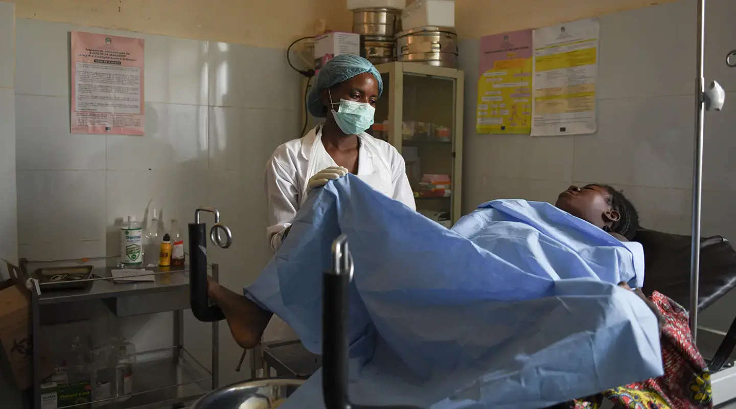 Dans la salle d’accouchement d’un hôpital, une femme accouche sous la supervision d’une agente de santé.