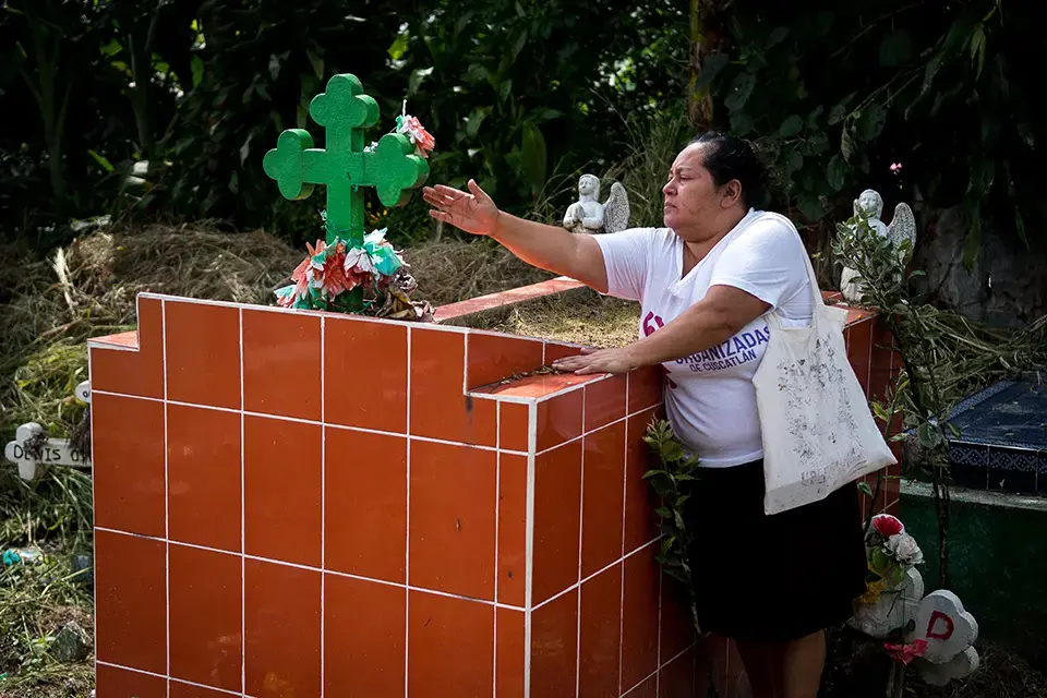 La amorosa tía Elena limpia la tumba de Cenia.
