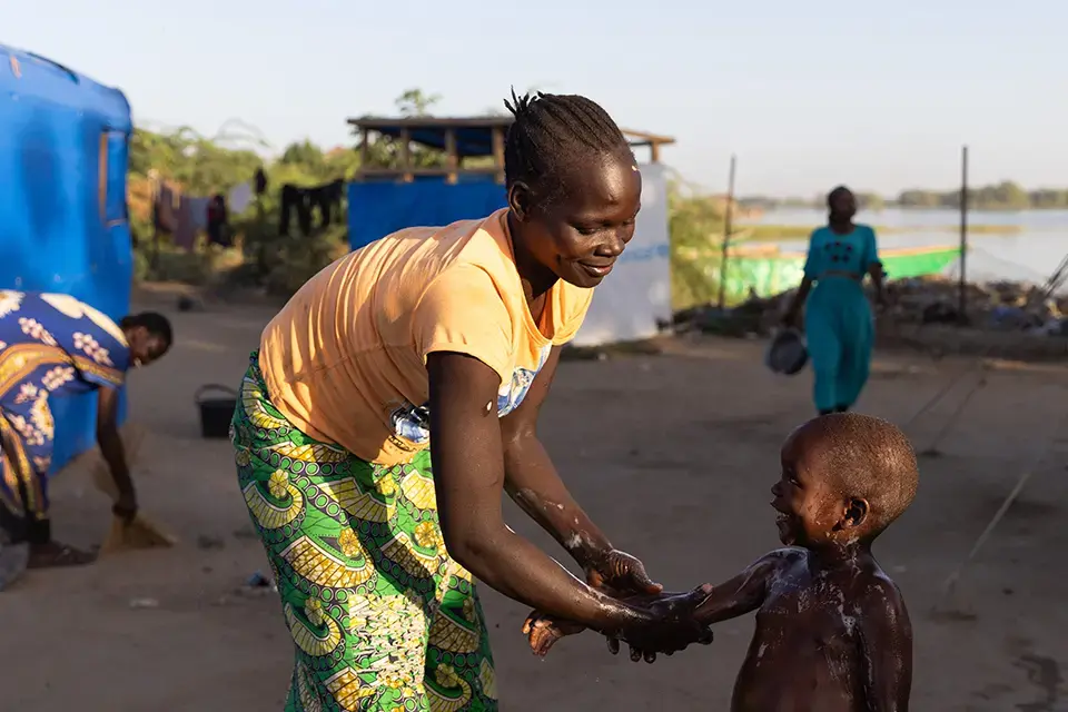 Une femme déplacée fait la toilette de son enfant au camp.